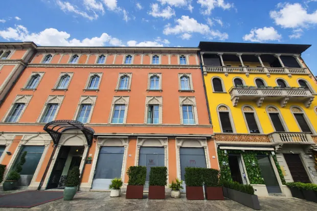 Meeting point at Piazza Cavour 26, Como — bright yellow façade beside the soft pink one
