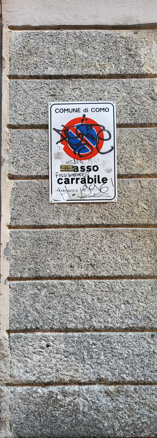 Comune di Como passo carrabile plate with the Italian no-parking disc on a stone wall